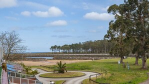 Une route côtière avec une voiture garée sur le bord, un sentier sinueux et une vue sur la plage et l’océan.
