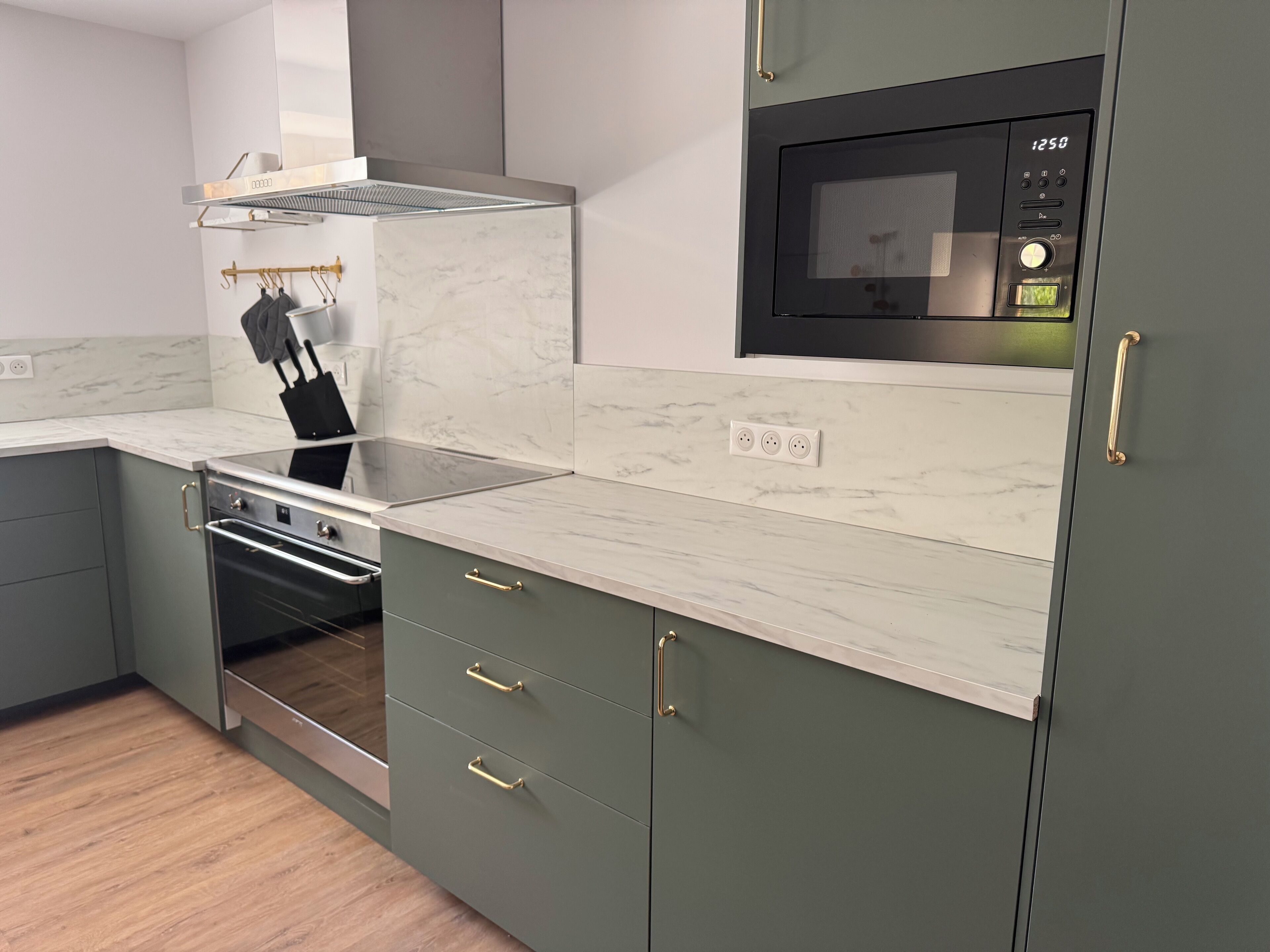 A modern kitchen with a built-in oven, microwave, and a stainless steel range hood.