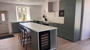 Una cocina moderna con una isla central, taburetes de bar, horno empotrado y una ventana que proporciona luz natural.