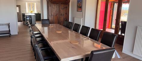 A conference room with a long table and chairs, a wooden cabinet, and a view through a glass door.