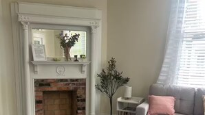 Un salon avec une cheminée, un canapé, une table basse et un tapis à motifs.