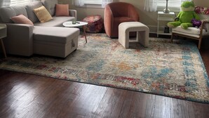 Un salon comprenant un canapé, un fauteuil, un pouf et une petite table avec une lampe.