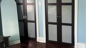 Une pièce dotée de deux portes en bois foncé, avec des panneaux en verre dépoli, d’un mur bleu clair et d’un plancher en bois.