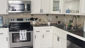 Une cuisine moderne avec des armoires blanches, des appareils en acier inoxydable et un plancher en bois.