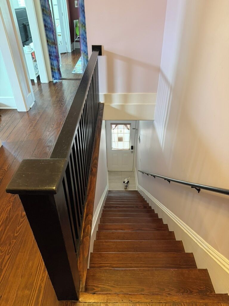 A wooden staircase with a handrail, leading to a door at the top.