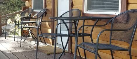 Une cabane en bois dotée d’un porche, comprenant un banc, deux tables et quatre chaises.