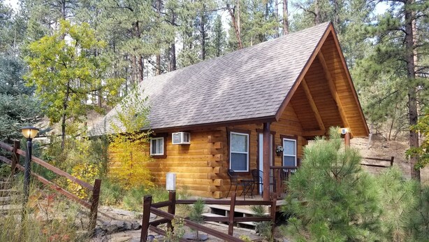 A cabin with a wooden exterior, a porch with chairs, and a wooden fence. - Timber Ridge #4 at Rustic Ridge (KEYSTONE)