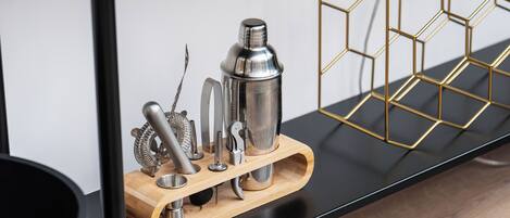 Een keukentafel met een houten dienblad waarop diverse keukengerei en een roestvrijstalen bak staan.