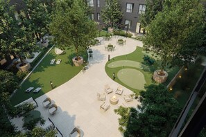 An outdoor courtyard with seating areas, a fire pit, and a golf putting green. - Luxury Apartments by Hyatus at Boston Everett (Everett)