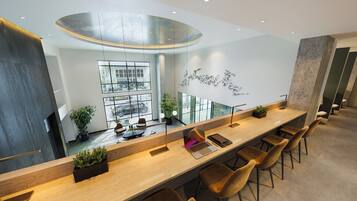 A modern bar area with a long counter, several chairs, and a large window providing a view of the outside.