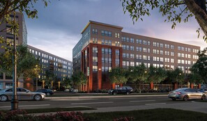 A modern multi-story building with a mix of glass and brick facades, surrounded by a well-maintained landscaped area with trees and flower beds. - Luxury Apartments by Hyatus at Boston Everett (Everett)