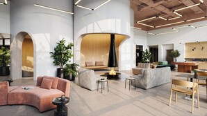 Een ruime lobby met een modern design, met een gebogen zithoek, een centraal haardelement en diverse zitmogelijkheden, waaronder banken en fauteuils.