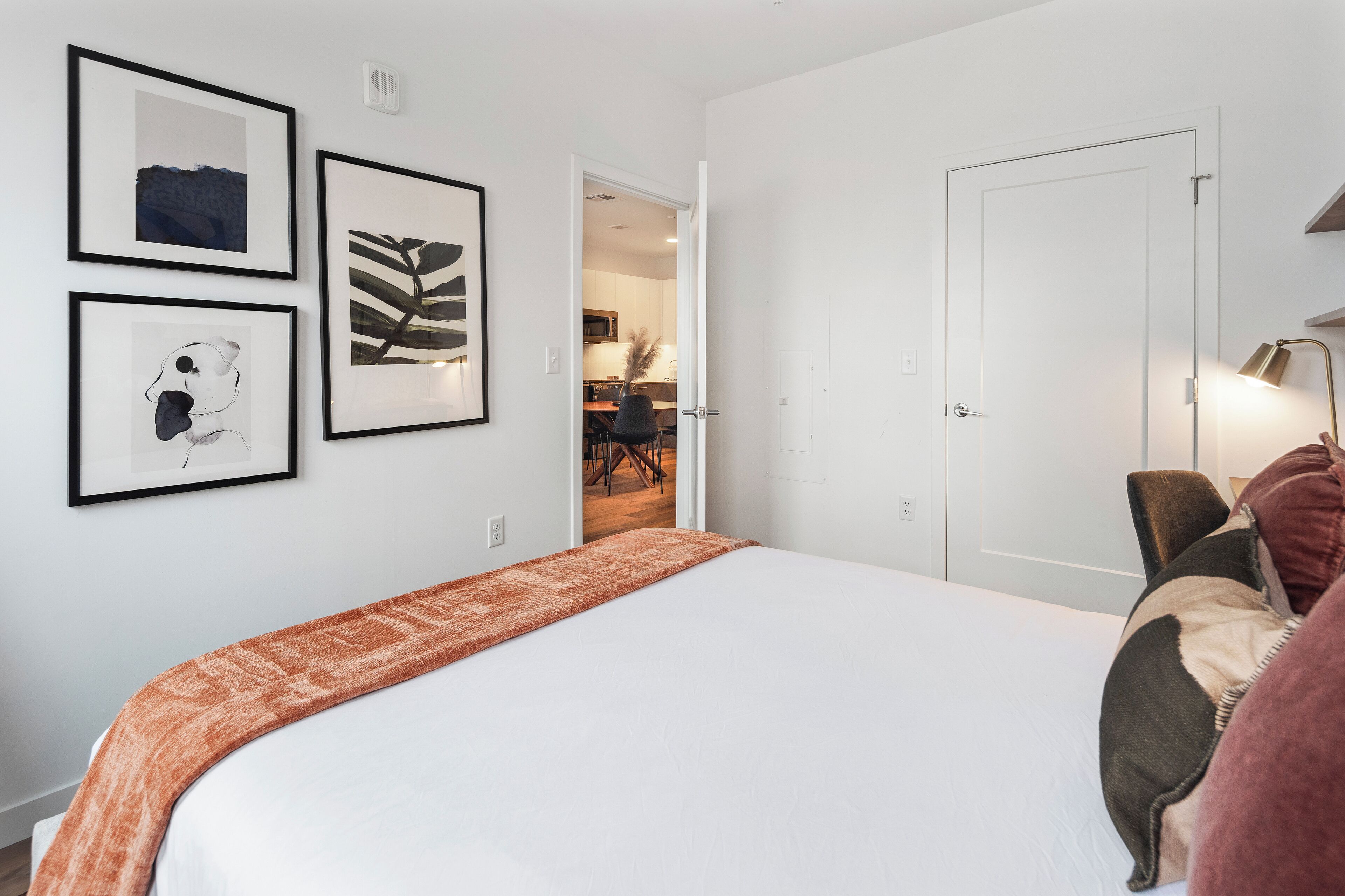Un dormitorio con una cama grande, una puerta y tres cuadros en la pared.