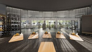 Een sportschool met oefenmatten, halters en een groot raam.