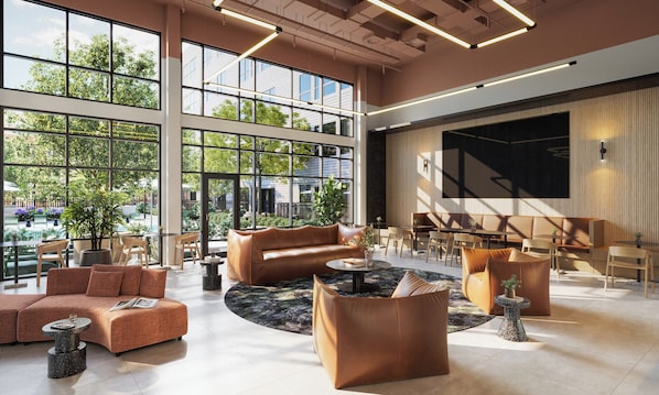 Un hall espacioso con ventanas amplias, una zona de estar central con sofás y sillones, y un diseño moderno con una pantalla grande en la pared.
