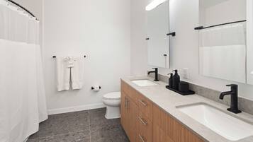 A modern bathroom with a double sink, wooden vanity, and a large mirror.