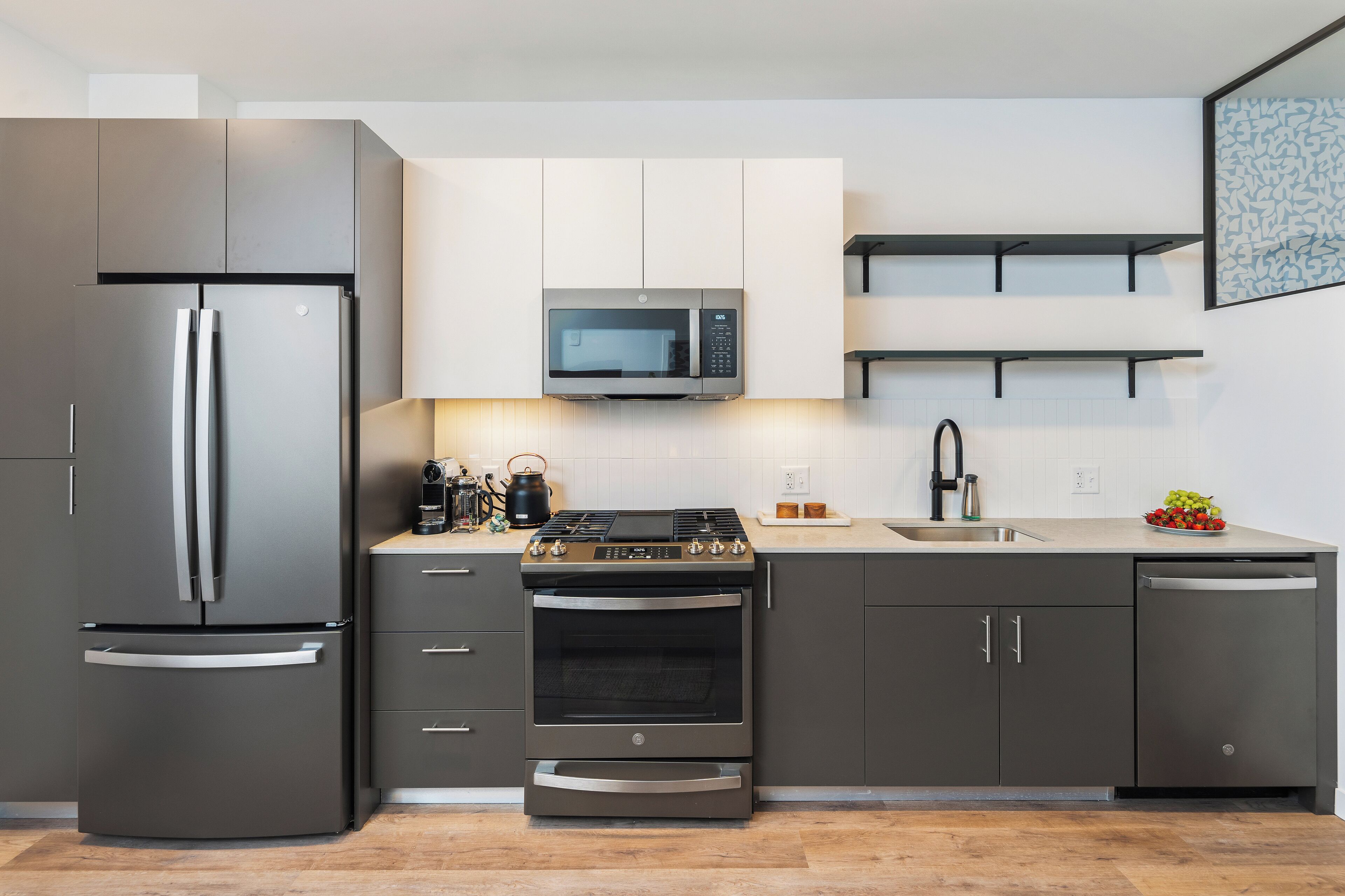 A modern kitchen with a stainless steel refrigerator, built-in microwave, gas stove, oven, and dishwasher.