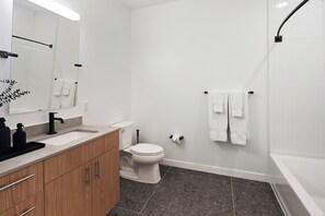 A modern bathroom with a white sink, toilet, and bathtub. - Luxury Apartments by Hyatus at Boston Everett (Everett)