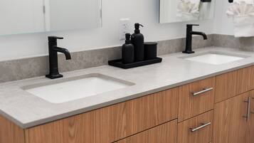 Une salle de bain moderne avec deux vasques, un robinet noir et un meuble en bois doté de tiroirs.
