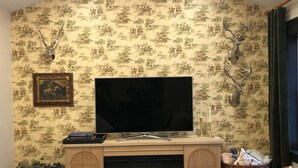 A living room with a fireplace, a television, and decorative wall art. - The Cottage (Mikana)