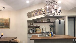 A kitchen with a central island, a chandelier, and a rustic decor theme. - The Cottage (Mikana)
