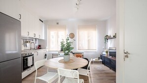 A modern kitchen with white cabinetry, a stainless steel refrigerator, and a dining area with a round table and white chairs. - Apartment in Sotrondio near the Nalon river (San Martin del Rey Aurelio)