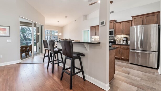 Una cocina moderna con refrigerador de acero inoxidable, armarios de madera y una zona de bar con taburetes.