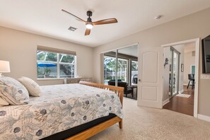 A bedroom with a bed, a ceiling fan, a window, and a door leading to a balcony. - Wow! Ultra-spacious 4/2 pet-friendly beach home w/pool, fenced-in yard, sleeps 8 (New Smyrna Beach)