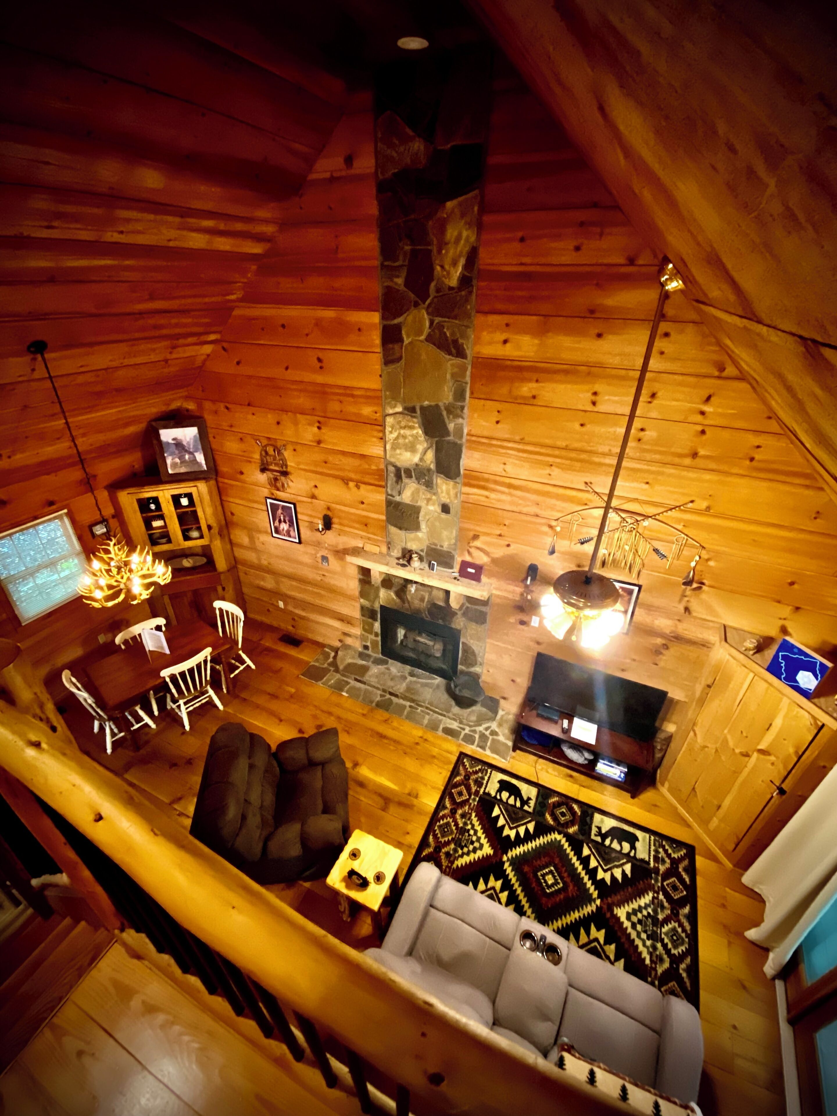 Ein gemütliches Blockhaus mit Kamin aus Stein, Holzwänden, einer Couch und einem Essbereich.