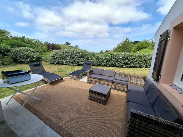 A patio area with wicker furniture, a table, and a grill. - Renovated, detached family home in Belle-Île, 3 bedrooms, sleeps 9 (Le Palais)