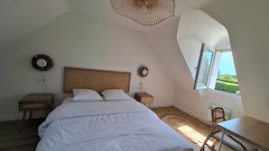 A bedroom with a bed, two bedside tables, a desk, a chair, a window, and a unique ceiling fan. - Renovated, detached belle-illoise family home, 3 bedrooms, sleeps 9 (Le Palais)