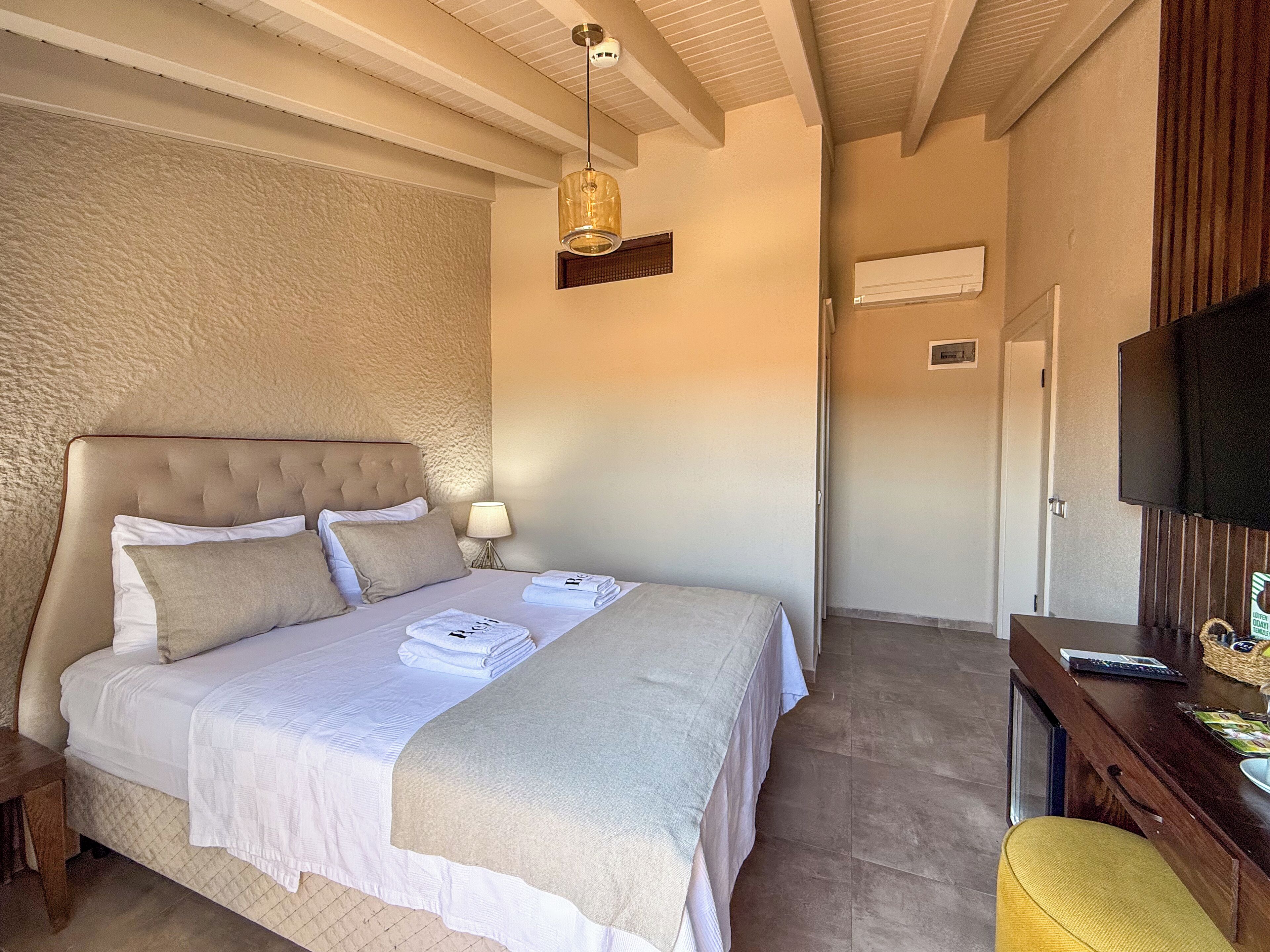 A neatly made bed with a headboard, a bedside lamp, and a folded towel on the bed.