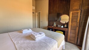 Una habitación de hotel con cama, escritorio, espejo y armario.