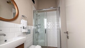 Un baño moderno con un lavamanos blanco, un inodoro y una ducha con mampara de vidrio.