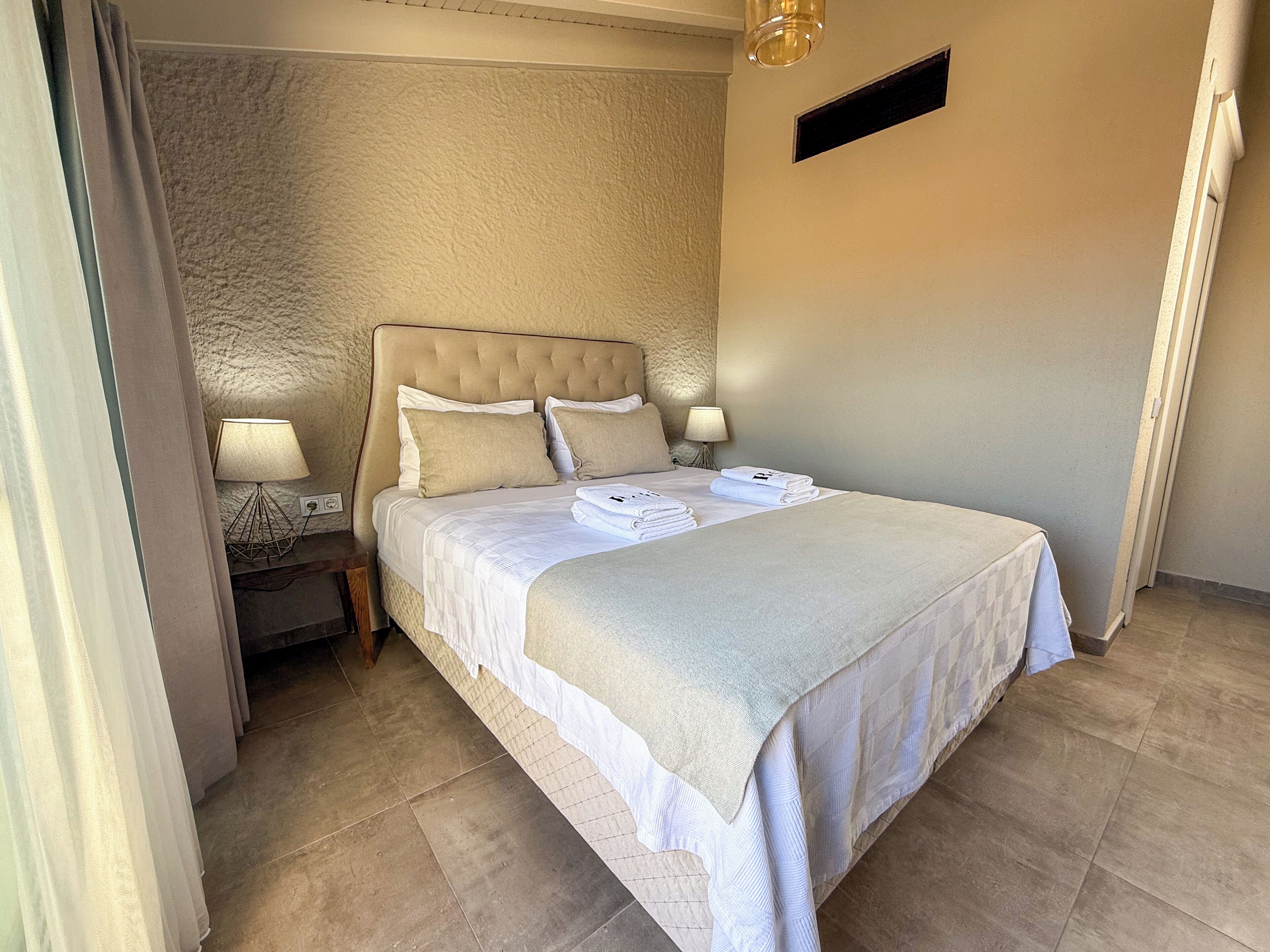 A neatly made bed with a headboard, two bedside lamps, and a folded towel on the bed.