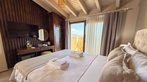 Habitación de hotel con una cama grande, un escritorio con silla, un espejo y vistas al exterior.