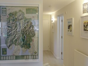 Un couloir orné d’une carte encadrée du parc national du Lake District, d’une œuvre d’art encadrée intitulée « Striding Edge », et d’une porte donnant sur une autre pièce.