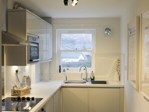 A kitchen with a window, sink, and cabinets. - 1 bedroom accommodation in Keswick (Keswick)