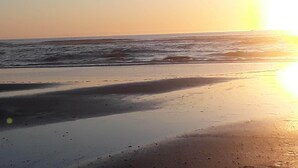 Una playa con olas y un atardecer.