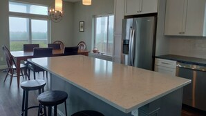 Una cocina moderna con una isla grande, electrodomésticos de acero inoxidable e iluminación colgante.