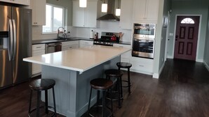 Una cocina moderna con una isla grande, electrodomésticos de acero inoxidable y taburetes de bar.