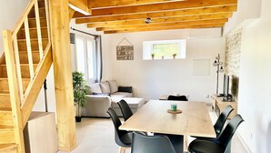 A modern living space with a wooden staircase, a dining area with a table and chairs, a sofa, and a potted plant. - Gîte de la Coopérative à L'Epine - 4/6pers - Wifi Terrasse Confort (L'Épine)
