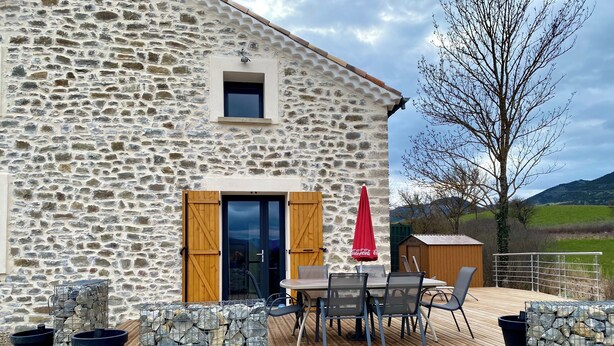 A stone building with a wooden deck, outdoor seating, and a red umbrella. - Gîte de la Coopérative à L'Epine - 4/6pers - Wifi Terrasse Confort (L'Épine)