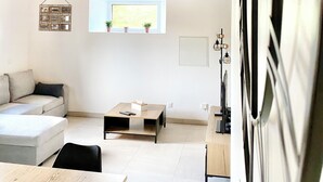 A modern living room with a wooden ceiling, a sofa, a coffee table, and a TV. - Gîte de la Coopérative à L'Epine - 4/6pers - Wifi Terrasse Confort (L'Épine)
