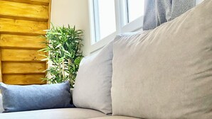 A modern living room with a beige sofa, a small potted plant, and a wooden accent wall. - Gîte de la Coopérative à L'Epine - 4/6pers - Wifi Terrasse Confort (L'Épine)