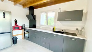 A modern kitchen with grey cabinets, a black range hood, a red microwave, and a stainless steel sink. - Gîte de la Coopérative à L'Epine - 4/6pers - Wifi Terrasse Confort (L'Épine)