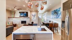 A modern kitchen with a large island, stainless steel appliances, and a flat-screen TV. - Mountain View Getaway - Groups Welcome! (Fort Collins)