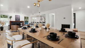 Un comedor moderno con una mesa de madera dispuesta para cuatro, rodeada de sillas con marcos dorados.