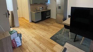 Eine kompakte Küche mit modernen Geräten, ein Essbereich mit Fernseher und Holzboden.