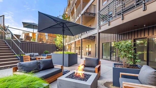 An outdoor seating area with a fire feature, modern furniture, and a staircase leading to an upper level. - Loftline Social - 8BR | 6BA | Sleeps 20 (Nashville)